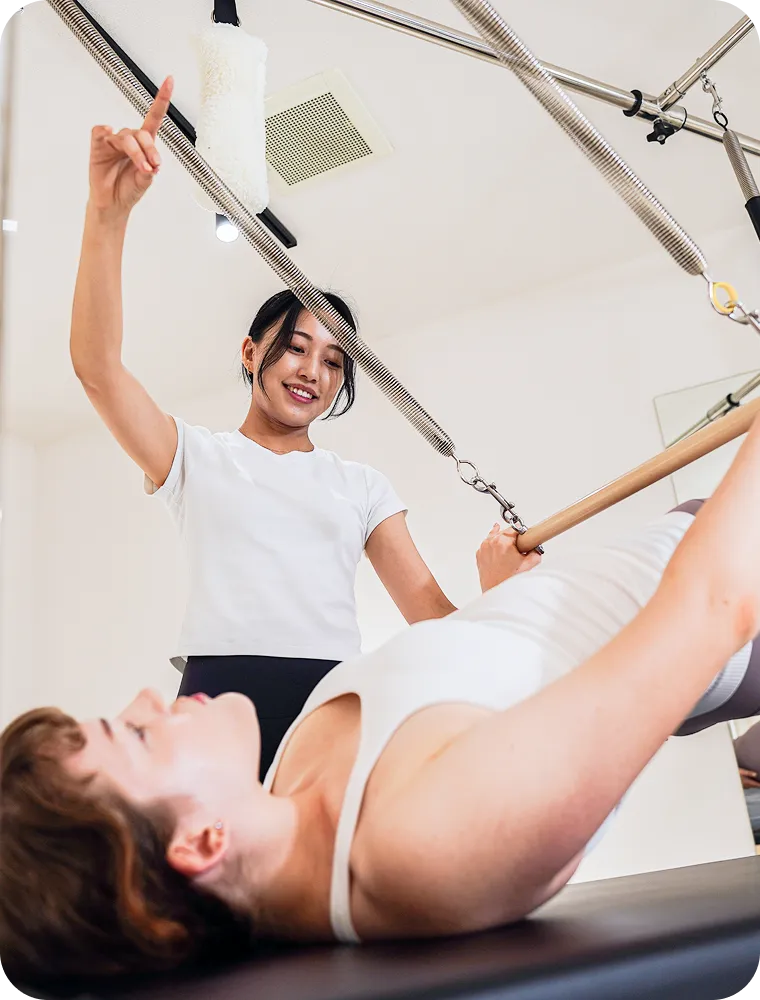 Instructor guiding a client through a Pilates session